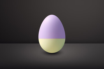 bicolor yellow and violet Easter egg in front of a black wall and on a black floor