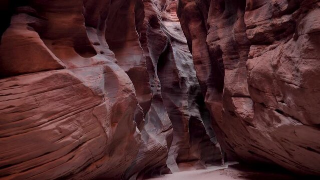 Moving forward along narrow deep slot canyon with smooth red sandstone rocks. Wavy walls of mysterious cave formed by erosion and precipitation. Antelope Canyon is popular place for photos and travel