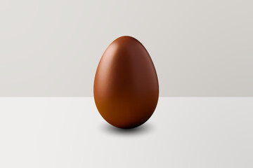 brown chocolate Easter egg in front of a white wall and on a white floor