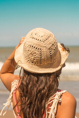 woman on the beach wearing crochet hat .Outfit spring summer