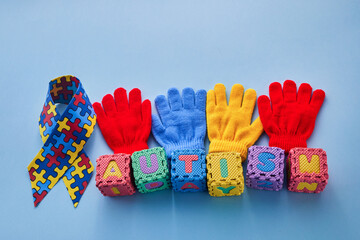 Word Autism Awareness day. Autism Awareness Ribbon and Puzzle cubes on blue background.