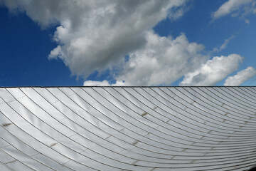 Metal sheet roof and slope with clouds and blue sky background.