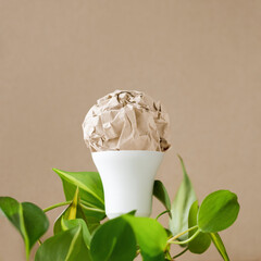 Creative lightbulb with green leaves on beige background. Concept of green energy and sustainability.