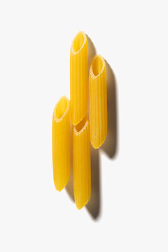 Four pieces of pasta penne on the white background.