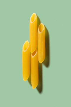 Four pieces of pasta penne on the green background.