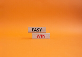 Easy win symbol. Wooden blocks with words Easy win. Beautiful orange background. Business and Easy...