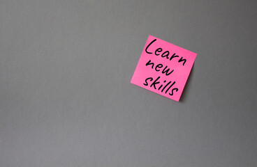 Learn new skills symbol. Concept words Learn new skills on pink steaky note. Beautiful grey background. Business and Learn new skills concept. Copy space.