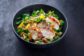 Traditional German lamb’s lettuce with chicken breast, fruit and cashew nuts served with spicy sweet and sour sauce as close-up on a Nordic Design bowl