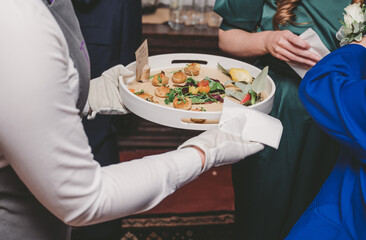 Close up of waiter or waitress holding tray of canapes