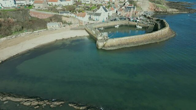 Crail, a historic fishing village on the east coast of Scotland in the East Neuk of Fife. Low level aerial footage of the pretty little harbour. Lovely reflections of whitewashed houses in the water.