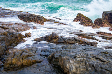 Beautiful tropical landscape. A stone ocean shore with waves and rocks. Beautiful texture background for tourism, design and advertising