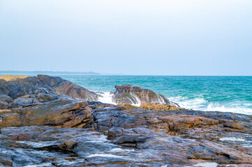 Beautiful tropical landscape. A stone ocean shore with waves and rocks. Beautiful texture background for tourism, design and advertising
