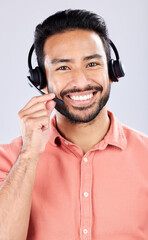 Portrait, call center and customer service with a man consultant in studio on a gray background. Contact us, crm or support and a happy male employee consulting with a headset for help or advice