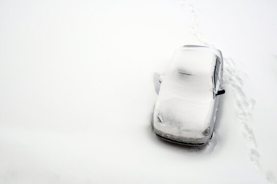 Lonely car on a snowy road. Human footprints in the snow.