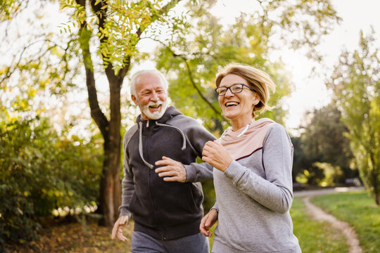 Smiling senior couple jogging in the park. Sports activities for elderly people.