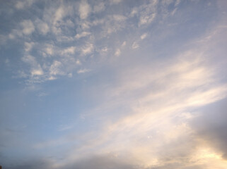 Somewhat diffused clouds in the sky of cream or orange color