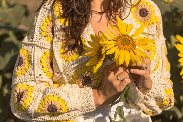 closeup of woman in crocheted cardigan holding sunflowers in hand, granny square sunflower, spring summer outfit