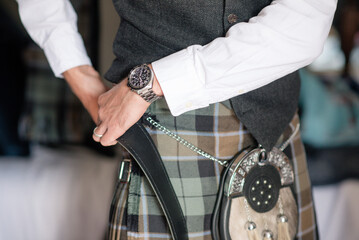 man or groom fastening his kilt belt close up