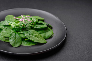 Fresh green spinach leaves on a black ceramic plate