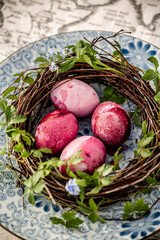 easter colored pink eggs in diy wreath from birch on blue plate with flowers
