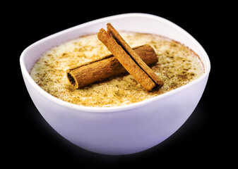 Creamy rice pudding sprinkled with cinnamon, typical Brazilian dessert, with cinnamon powder and cinnamon stick