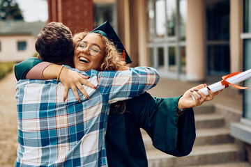 Supportive father congratulates his graduate daughter after receiving diploma at university.