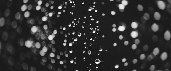 Obraz premium Atmospheric minimal grayscale backdrop with rain droplets on glass. Wet window with rainy drops and dirt spots closeup. Blurry minimalist monochrome background of dirty window glass with raindrops.