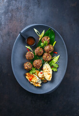 Traditional Asian street food meatballs served with tempura vegetables and spicy chili sauce as top view on a design plate with text space