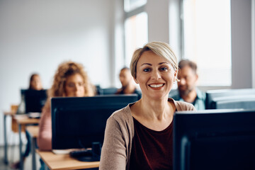 Happy woman attending computer class and looking at camera.