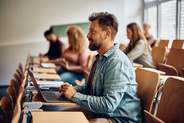 Mature student using laptop while attending lecture at university.