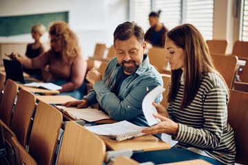 Adult students cooperating while learning together at lecture hall.