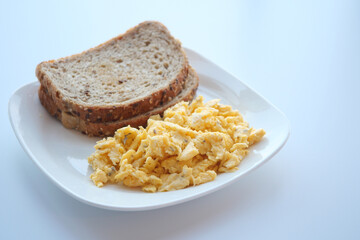 morning breakfast with Scrambled eggs on a bread on white plate 