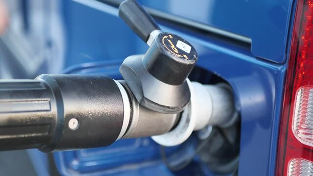 A man attaches a gas nozzle to a compressed natural gas CNG powered car
