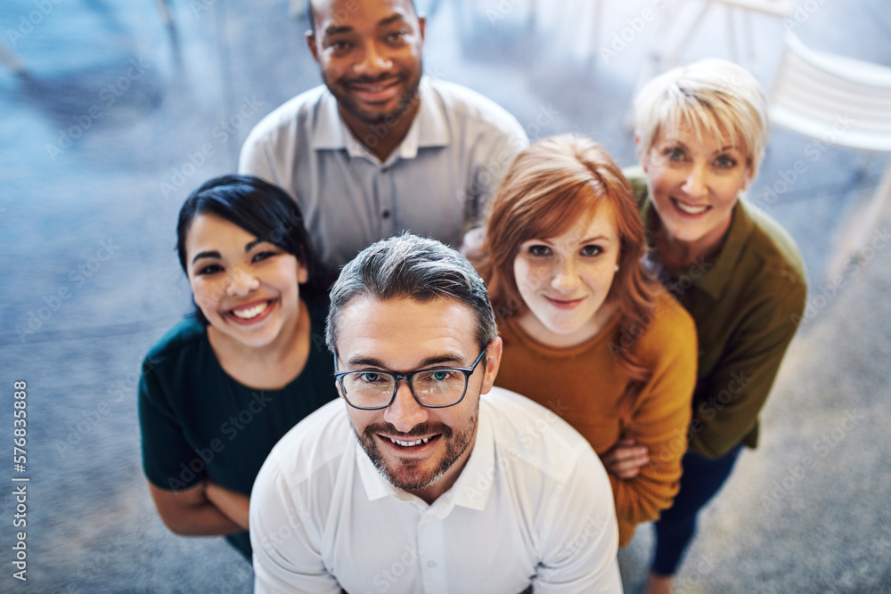 Poster working together to move on up. high angle portrait of a team of colleagues standing together in a m