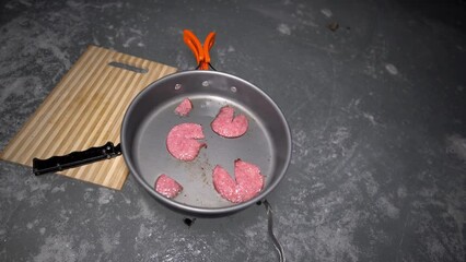 A guy cooks food on gas inside an ice cave. The climber lights the burner, cuts sausage and tomato. Breaks the eggs and fry in a frying pan. Steam from food. The ice wall is blue and the floor is gray - Powered by Adobe