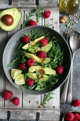 Avocado salad with arugula, raspberries and sunflower seeds. Top view. Healthy food.