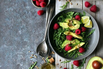 Avocado salad with arugula, raspberries and sunflower seeds. Top view. Healthy food.