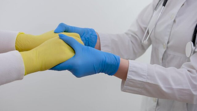 Doctor's hands in gloves holding man's hands. Medical background with copy space Care concept blue and yellow gloves flag of Ukraine aid to refugees medical care in medical institutions war in Ukraine