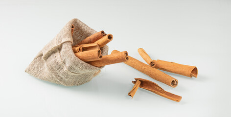 Jute bag with tubes of dried cinnamon on a light background
