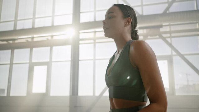 Athletic woman engaged in sports routine, relaxing after heavy training in a smokey gym interior