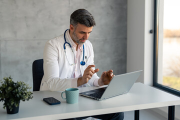 Dedicated male professional doctor offering support or medical advice to a patient during online medical appointment consultation, talking explaining, using laptop. Telemedicine and healthcare concept