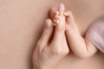 Close-up little hand of child and palm of mother and father. The newborn baby has a firm grip on the parent's finger after birth. A newborn holds on to mom's, dad's finger.