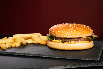 delicious fresh juicy beef patty burger and french fries in bulk on a slate cutting board