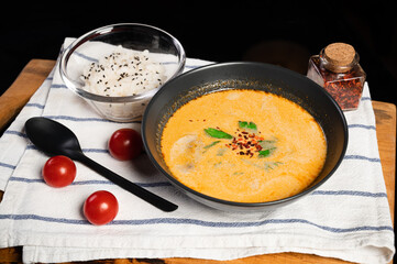 Tom yum soup in a bowl and with a bowl of rice lie on a cloth napkin and a wooden tray. exotic healthy asian food