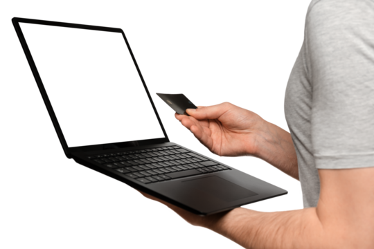 A man in a T-shirt holds a laptop, an ultrabook and a bank card with his second hand, makes an online purchase.