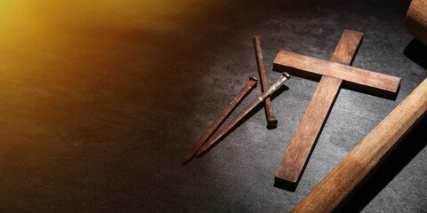 Wooden cross, nails and mallet on dark background with space for text. Good Friday concept