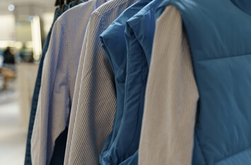 Sleeveless shirts and jackets hang on hangers in the store