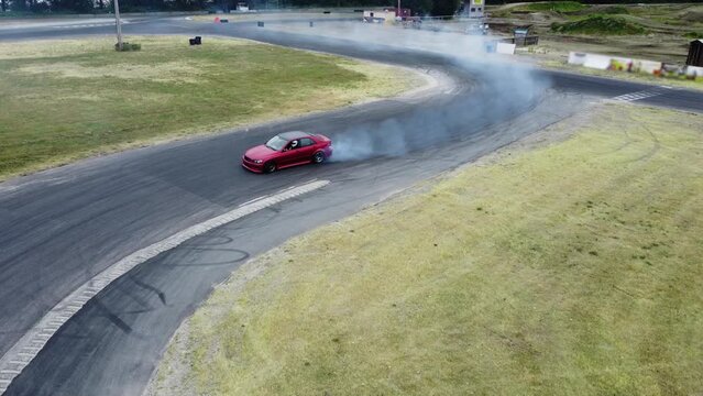Red Drift Car / Race car drifting around corner very fast with lots of smoke from burning tires on speedway / racetrack / drift track. Lexus is300 v8. JDM car.