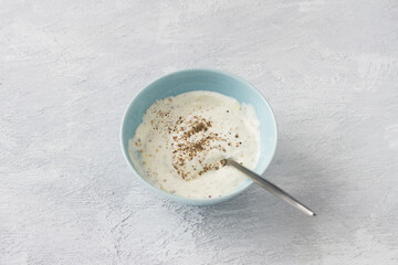 Bowl with sour cream or yogurt, mayonnaise, grain mustard and spices on a light gray background. Salad dressing preparation
