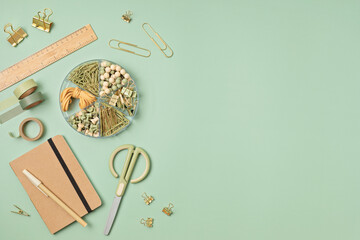 Flatlay of office supplies made of recycled materials on green background with copy space for text. Banner, flat lay, top view